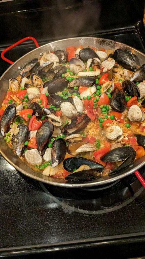 A pan full of Paella with mussels, clams, tomatoes, and rice.